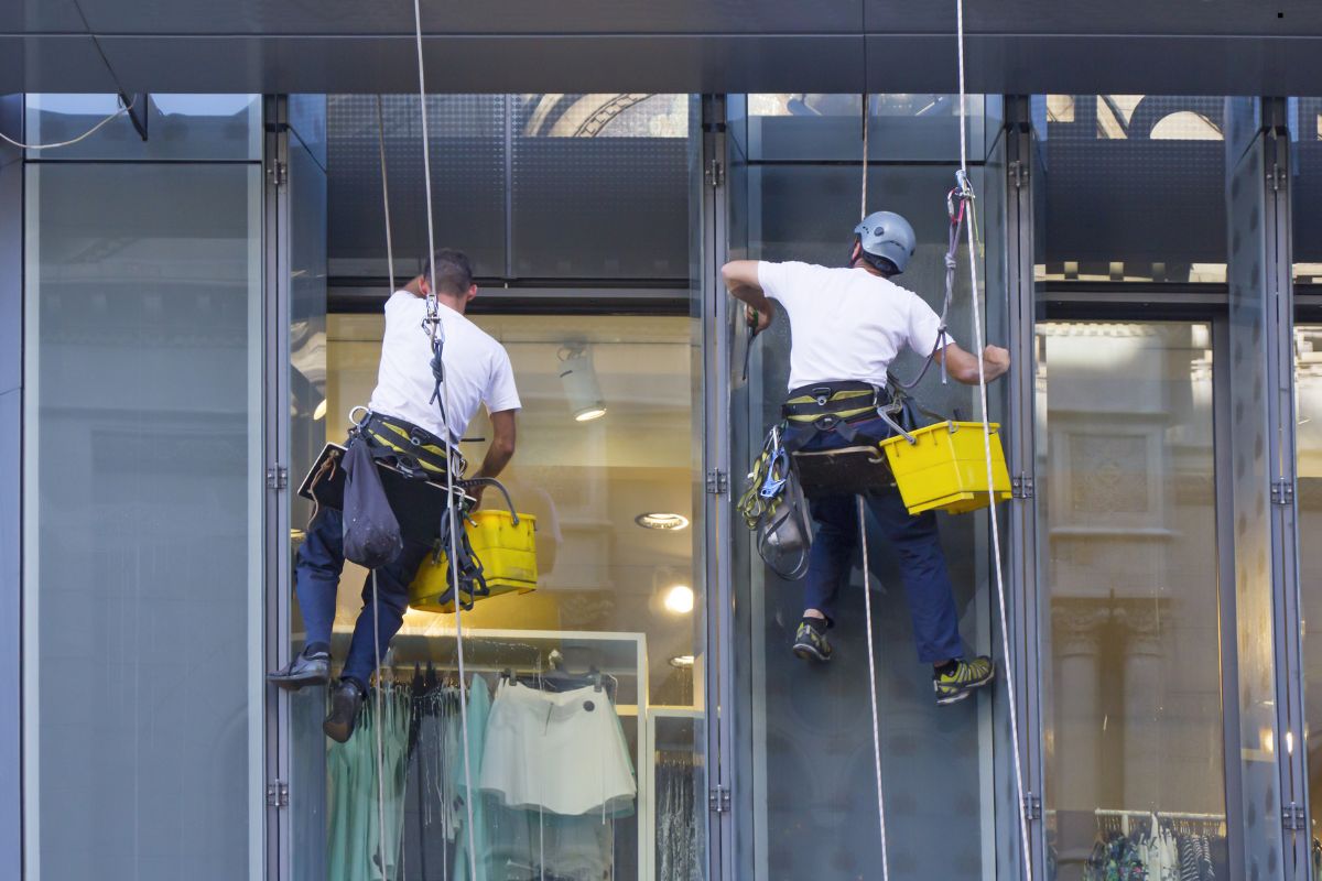 Two men performing window cleaning on a high-rise building, showcasing professional window cleaning services in action.